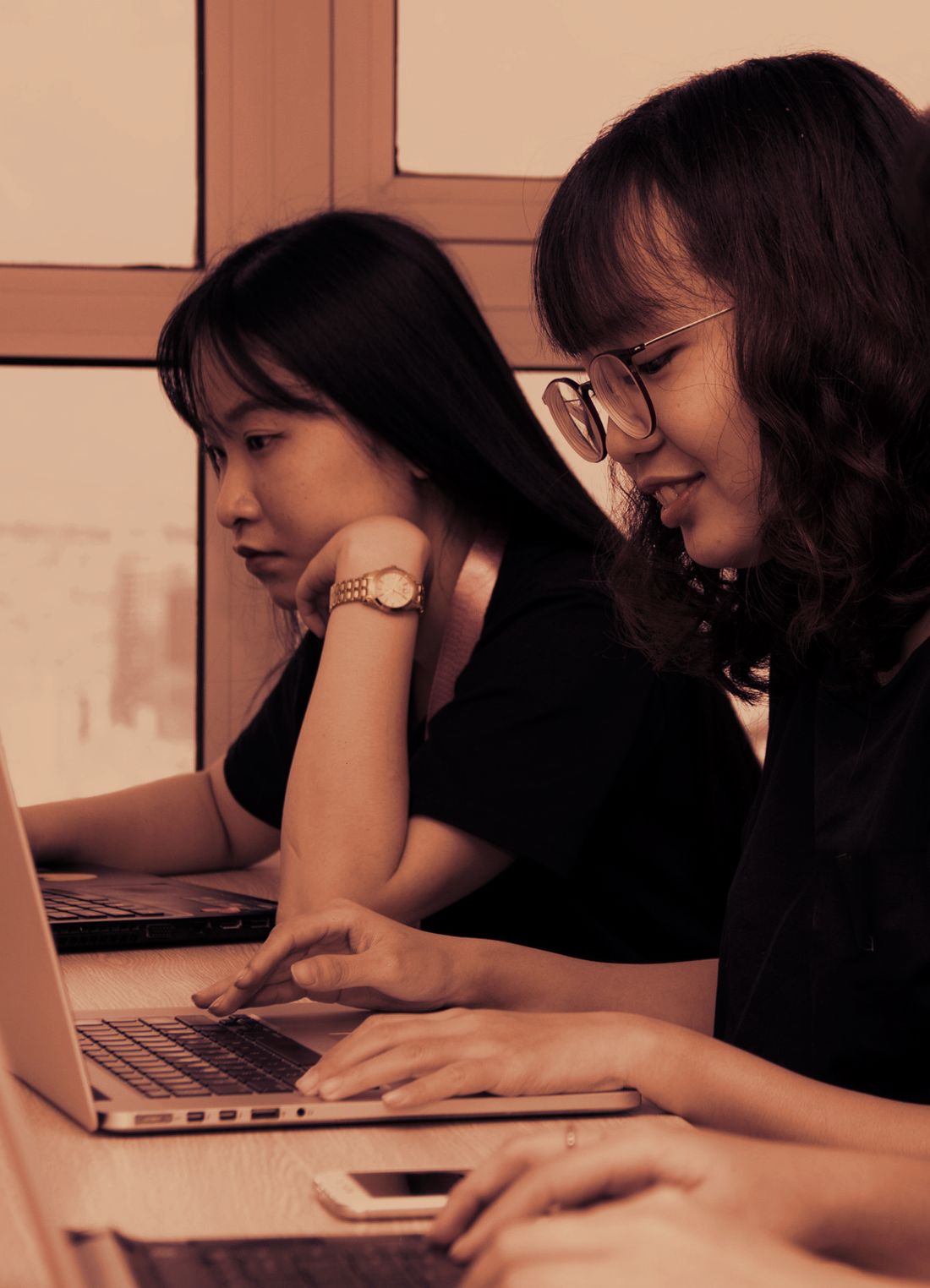Two colleagues working through a task together on their laptops