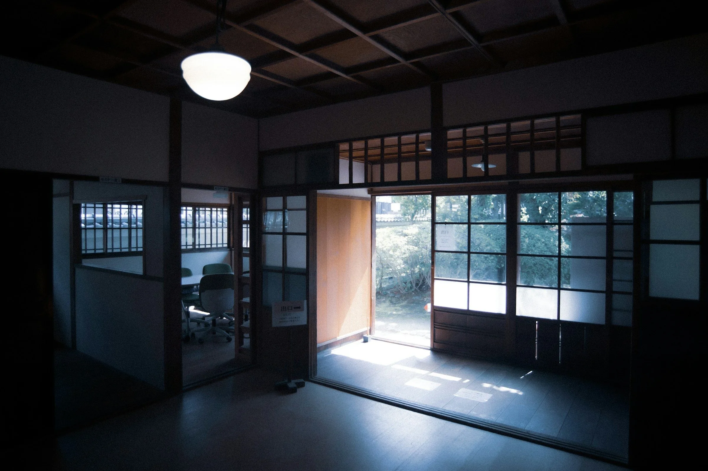 Sunlight through open glass doors into a dark room of the same house