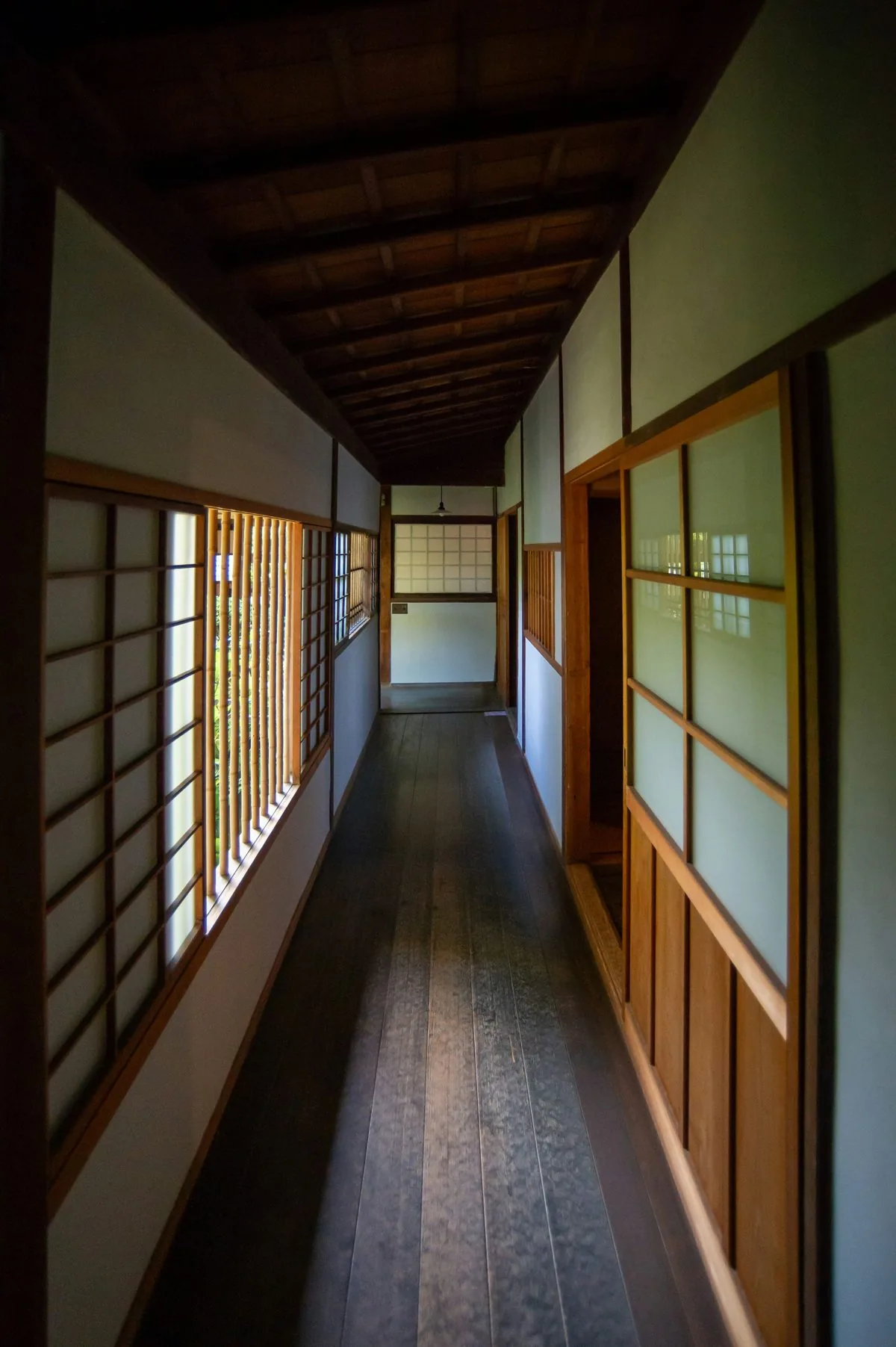 A long wooden hallway lined with shoji screens and garden windows