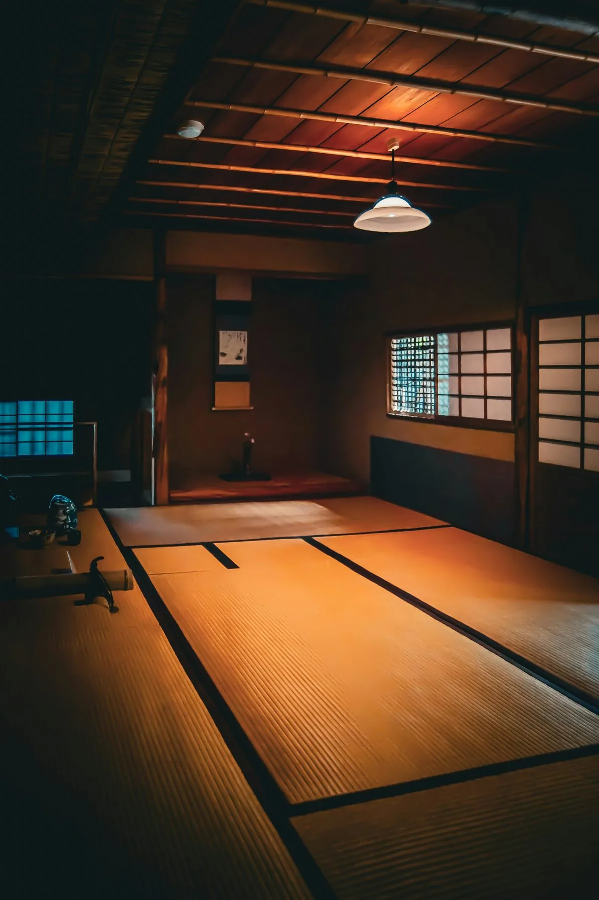 A tatami room in warm lamplight with shoji windows along the wall