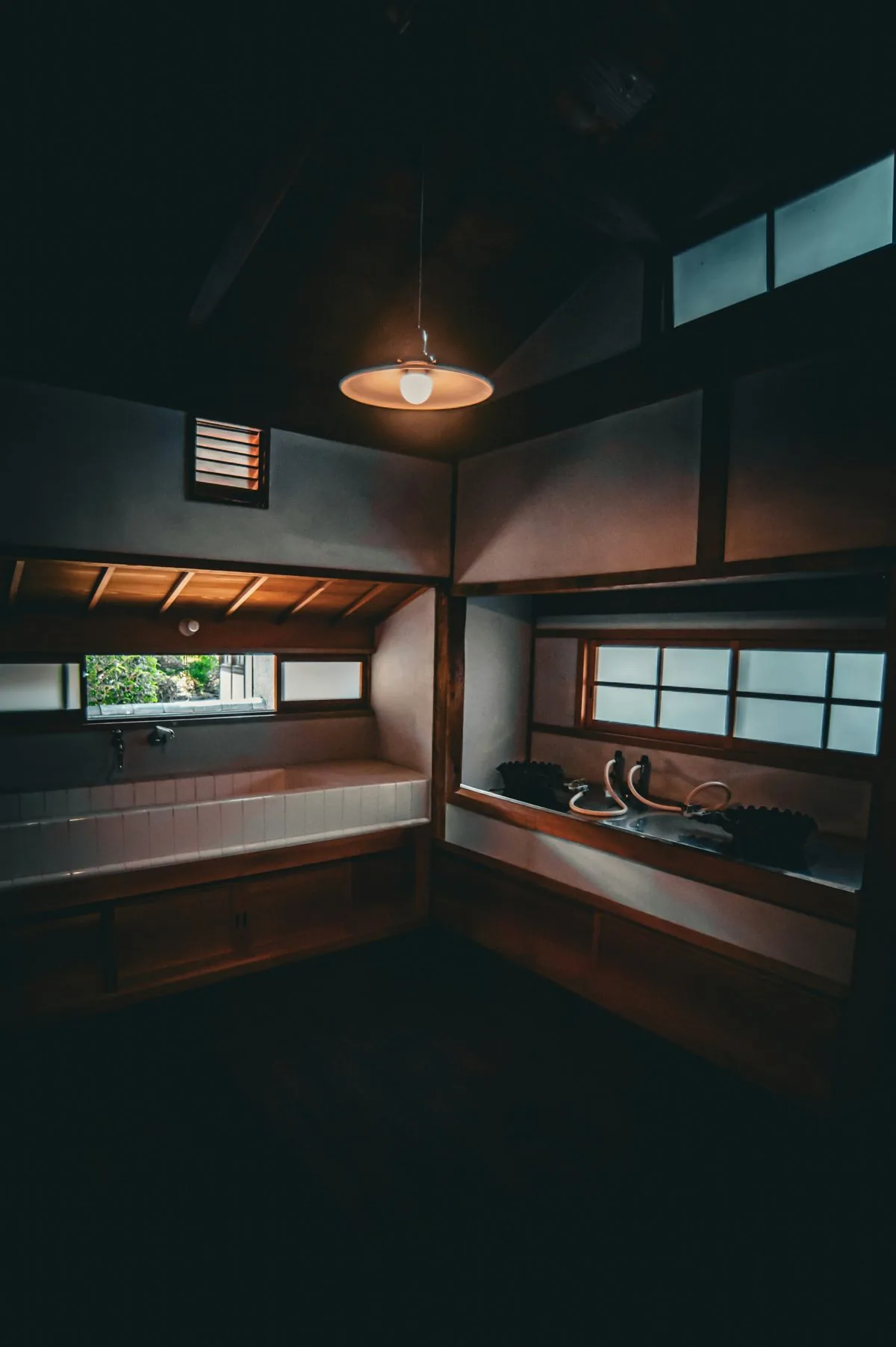 A bath room with wooden tubs under a hanging lamp
