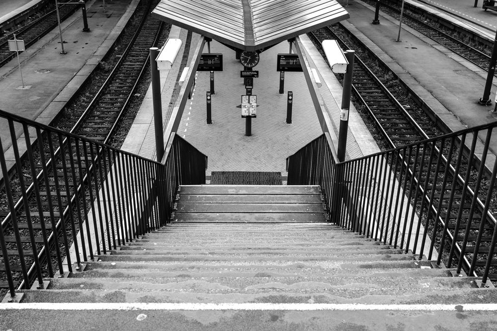 Black and white stairs descending to an empty railway platform