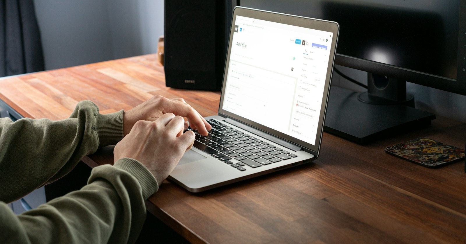 Person typing on a laptop showing the WordPress dashboard on a wooden desk — WordPress with Elementor Pro